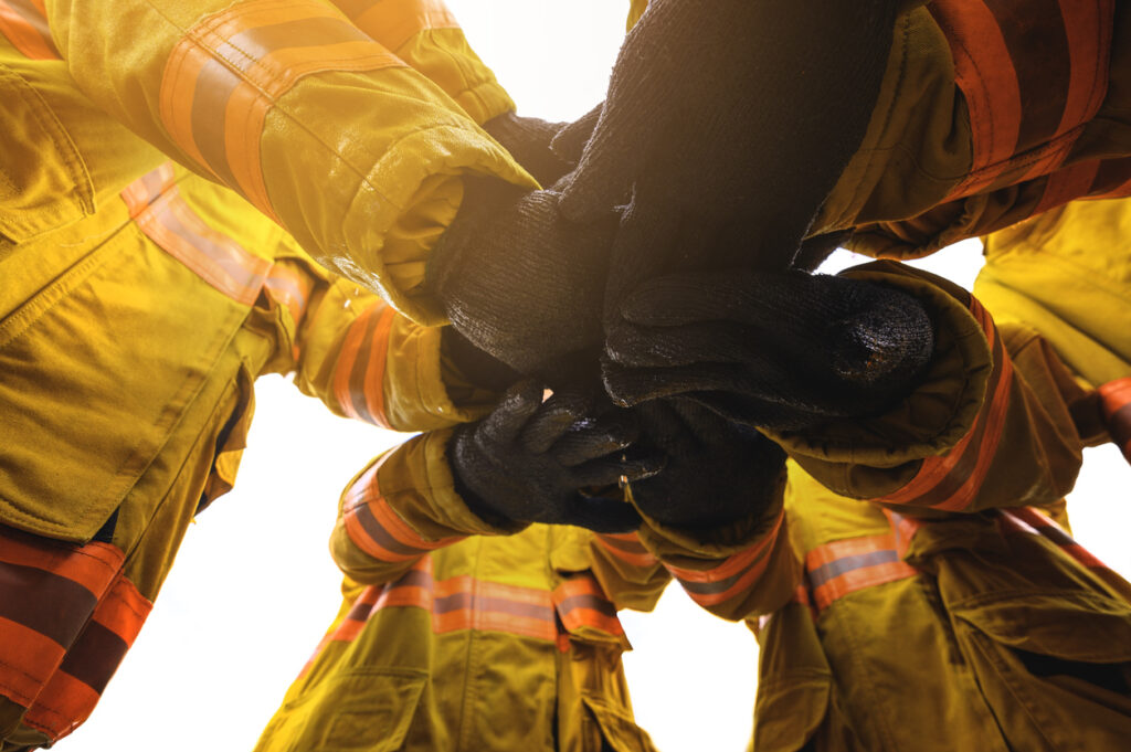 Firefighter putting hands up for fire fighting, Cheerful people giving strength motivation. Teamwork concept