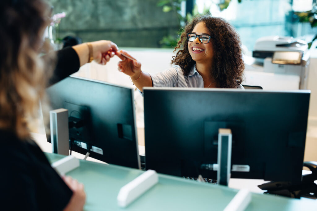 Female receptionist giving back the card to the woman at front desk. Friendly administrator assisting a female at municipal office.