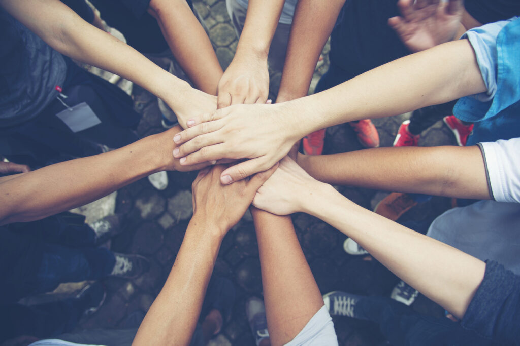 Young People Putting Their Hands Together On Top Of Each Other.Solidarity unite people hands together community teamwork.